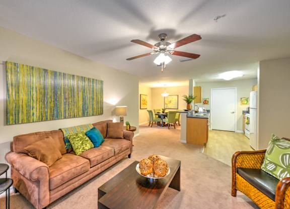 A living room with a brown couch and a ceiling fan.