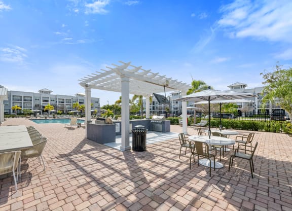 an outdoor patio with tables, grills and chairs and a swimming pool