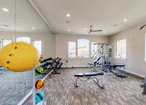A gym with a yellow ball, weights, and exercise equipment.