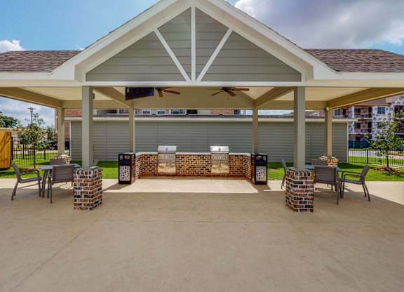 A covered patio area with a brick fireplace and seating area.