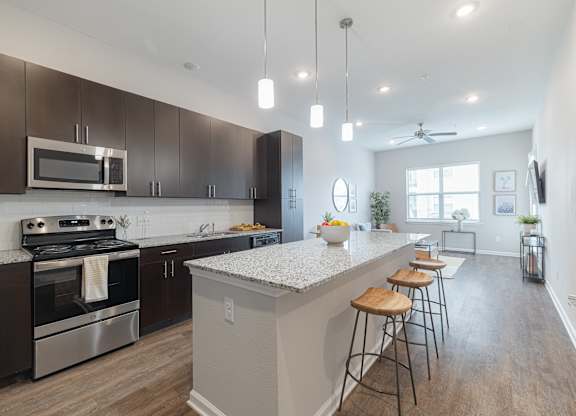 A modern kitchen with dark brown cabinets and stainless steel appliances.