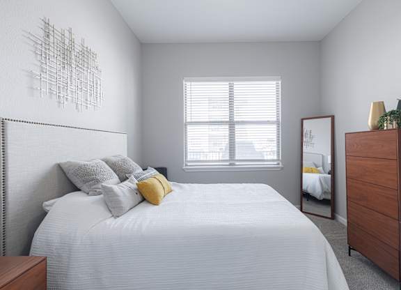 A bedroom with a bed, dresser, and mirror.