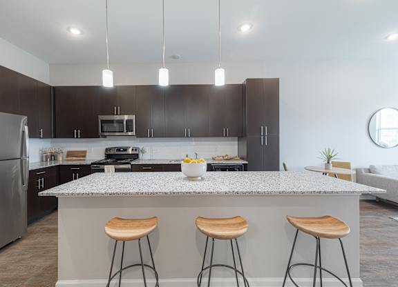 A modern kitchen with a granite countertop and bar stools.