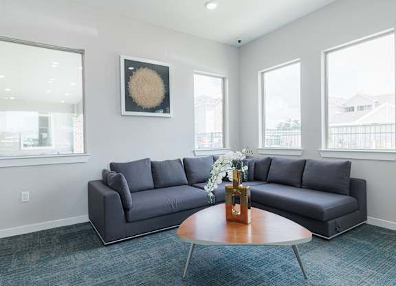 A grey couch sits in a room with a round table in front of it.