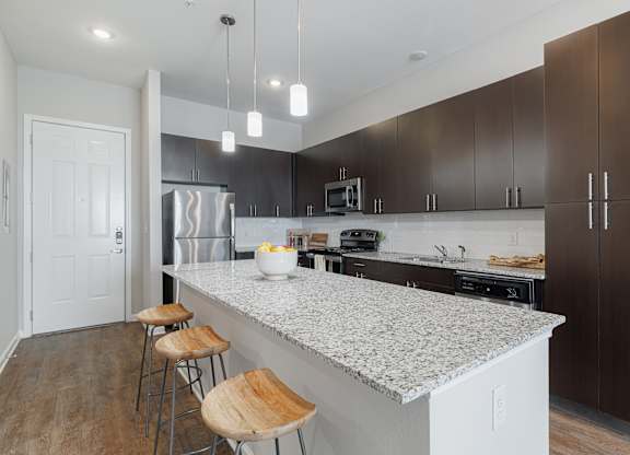 A kitchen with a white countertop and brown bar stools.