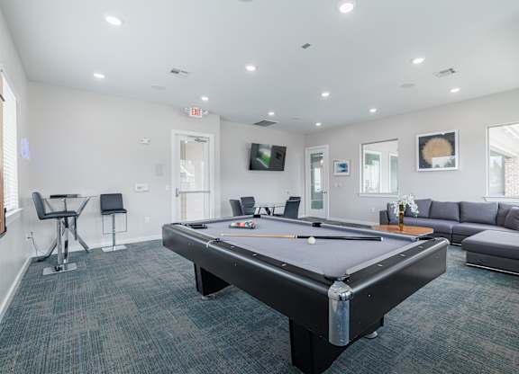 A room with a pool table and a couch.