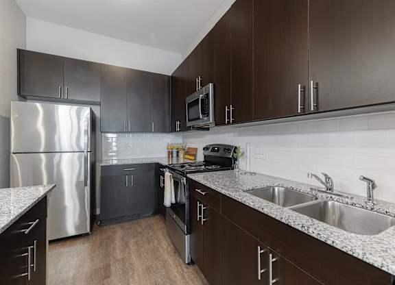 A modern kitchen with dark brown cabinets and stainless steel appliances.