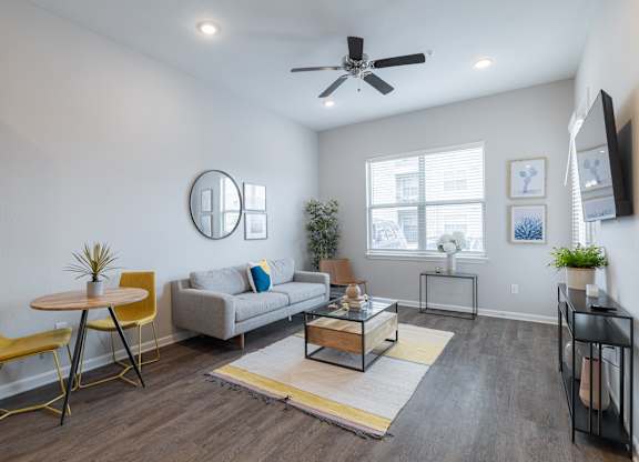 A living room with a yellow chair and a grey couch.