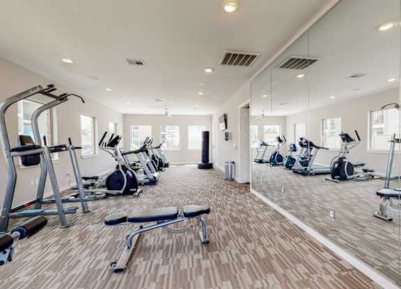 A spacious gym with a variety of equipment including treadmills, stationary bikes, and weight machines.