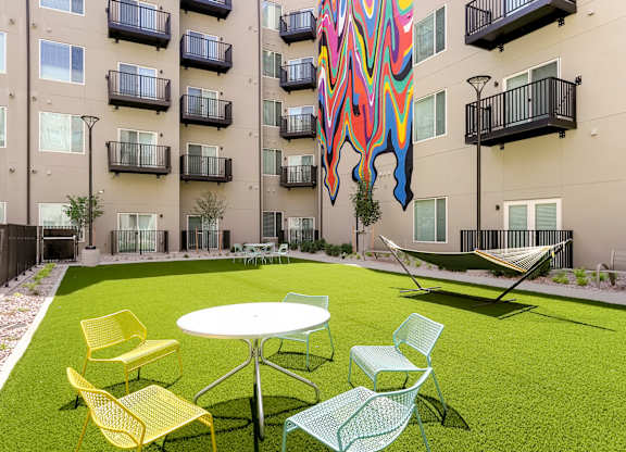 A patio with a table and chairs in front of a building.