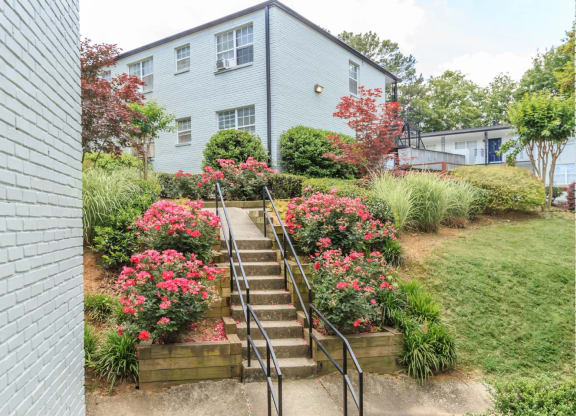 a staircase leading up to a blue house with pink flowers in front of it