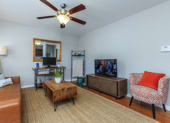 a living room with a ceiling fan and a tv