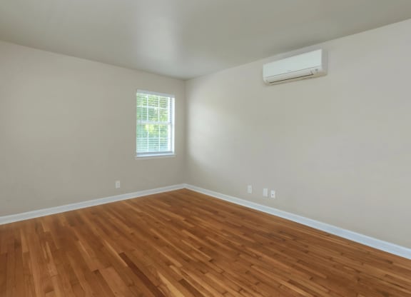 an empty room with a window and wooden floors