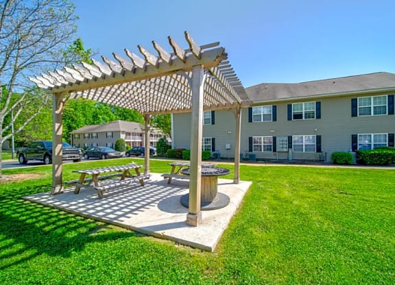 a picnic area with a pergola in front of an apartment building