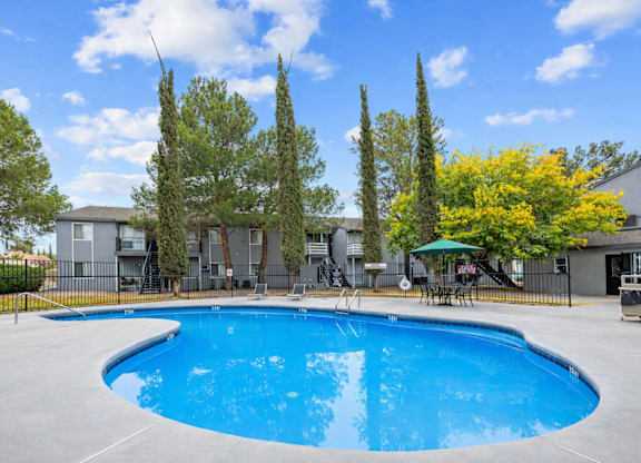 A swimming pool surrounded by trees and a building in the background.