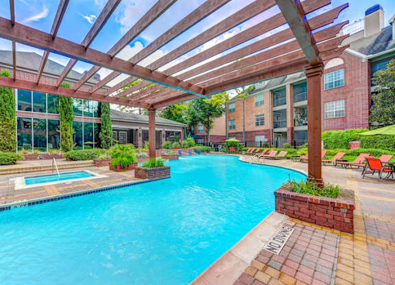 A large outdoor swimming pool with a wooden pergola over it.
