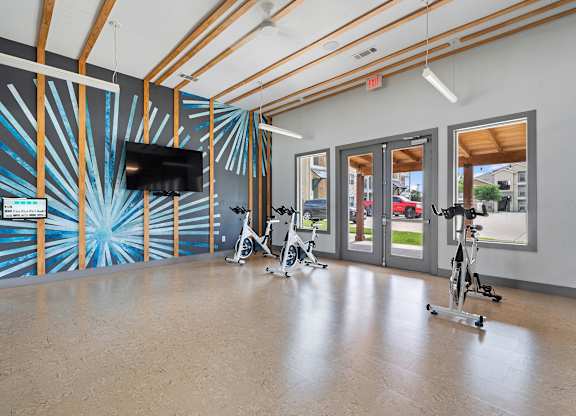 A room with exercise bikes and a TV on the wall.