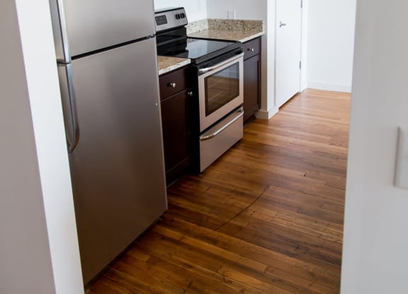 a small kitchen with stainless steel appliances and a wooden floor