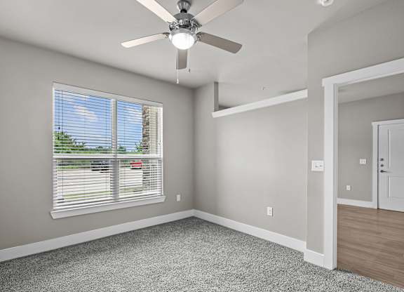 an empty bedroom with a ceiling fan and a window