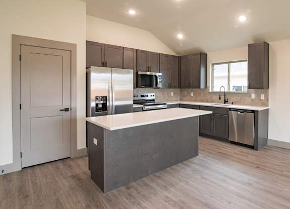 A modern kitchen with a large island and stainless steel appliances.
