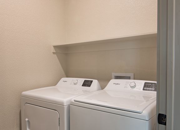 Two white washing machines in a small laundry room.