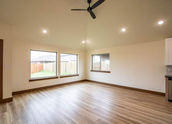 A room with a ceiling fan and two windows.