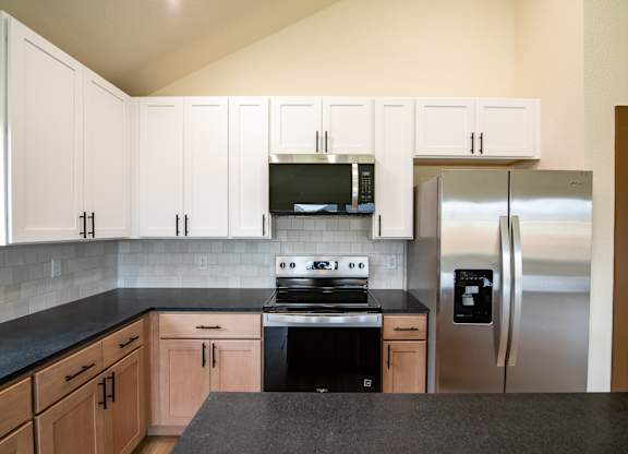 A kitchen with black countertops and stainless steel appliances.