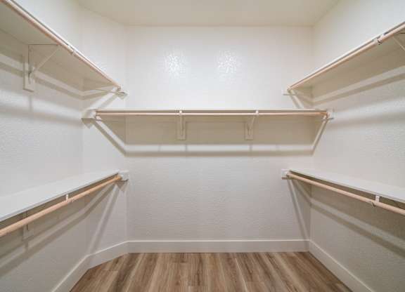 Empty white refrigerator with wooden floor and white walls.