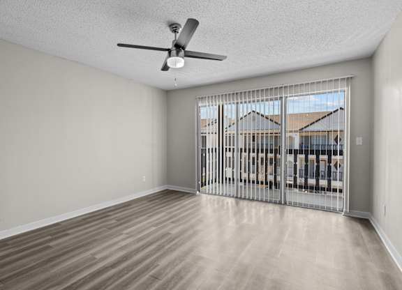 an empty living room with a large window and a ceiling fan