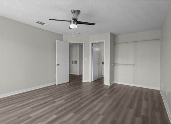 an empty living room with wood flooring and a ceiling fan