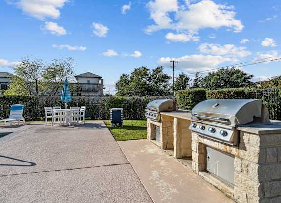 a patio with a barbecue grill and a table and chairs