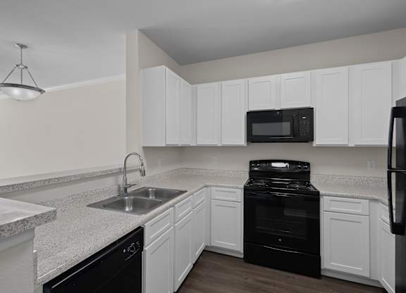 a kitchen with white cabinets and black appliances