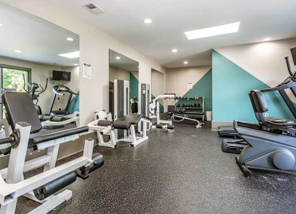 A gym with a variety of equipment including treadmills, weights, and exercise machines.