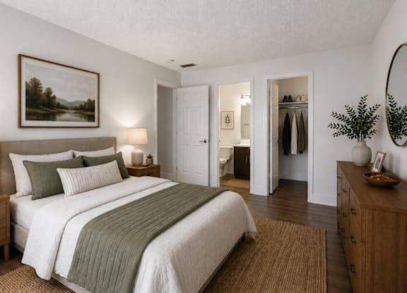 A bedroom with a large bed and a painting on the wall.