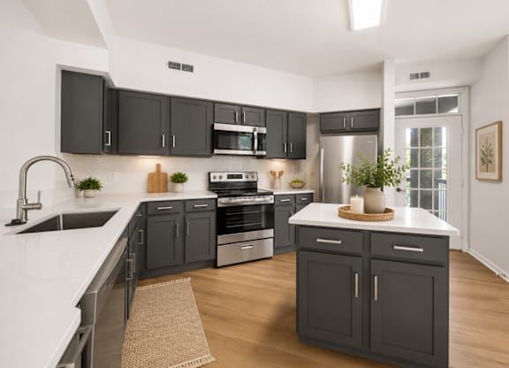 A modern kitchen with dark grey cabinets and white countertops.