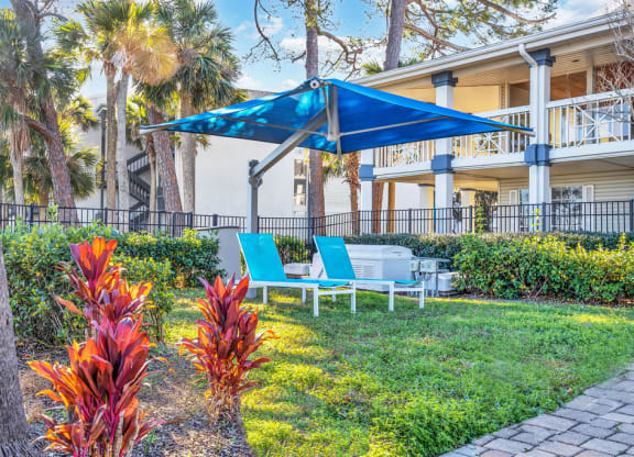 a patio with a blue umbrella and chairs in front of a building