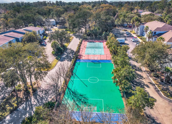 an aerial view of a basketball court and tennis court in a neighborhood with trees