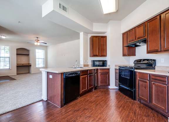 an empty kitchen with wooden cabinets and black appliances