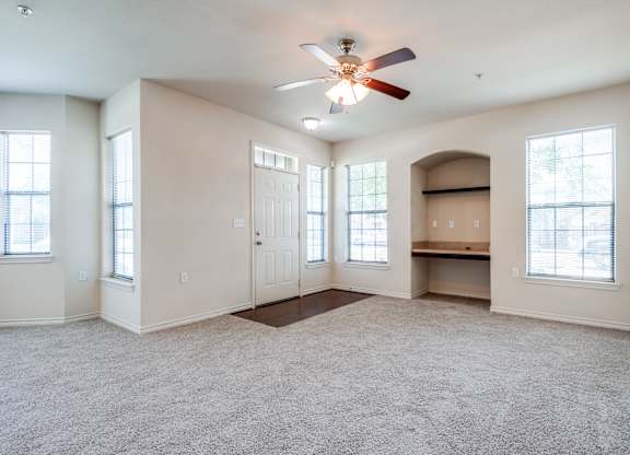 an empty living room with a ceiling fan