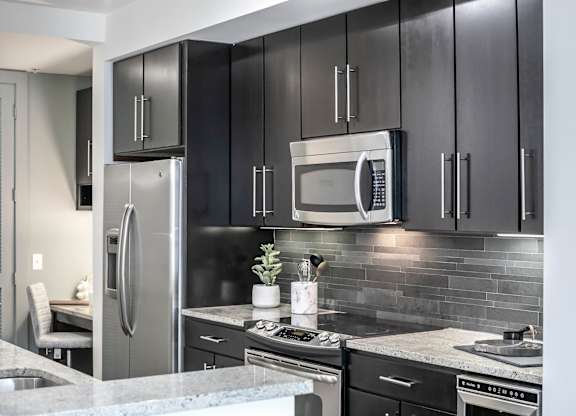 A modern kitchen with a stainless steel refrigerator and microwave.