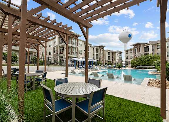 a patio with a table and chairs next to a swimming pool