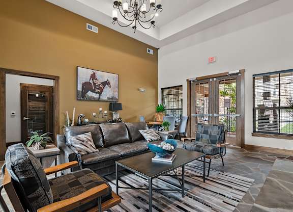 A living room with a brown sofa and a painting of a horse and rider on the wall.