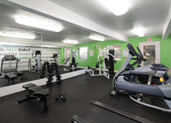 A gym with a variety of equipment including treadmills, weights, and exercise machines.