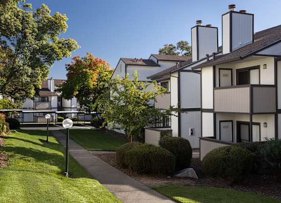 A white building with a black roof and a sign on the lawn.