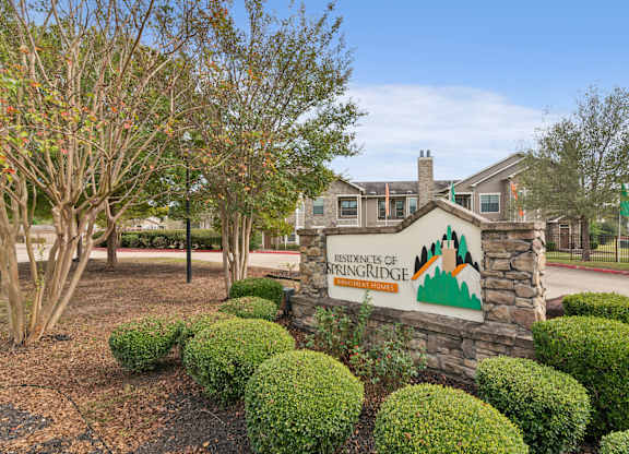 A sign for the residents of Springridge in front of a building and trees.