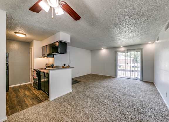 an empty living room and kitchen with a door to a balcony