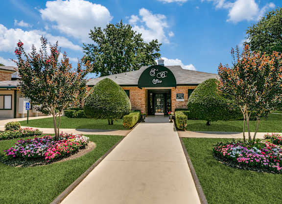 an exterior view of a brick building with a green awning and landscaping