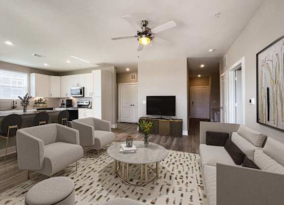 A modern living room with a white sofa, grey armchairs, and a patterned rug.