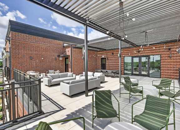 A patio with a white couch and green chairs.