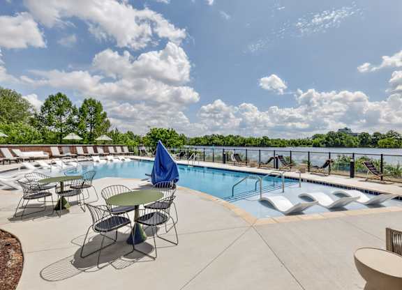 A pool area with chairs and a table.